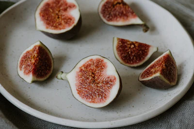 Close-up of a hand placing a fresh fig on a beautifully arranged charcuterie spread.