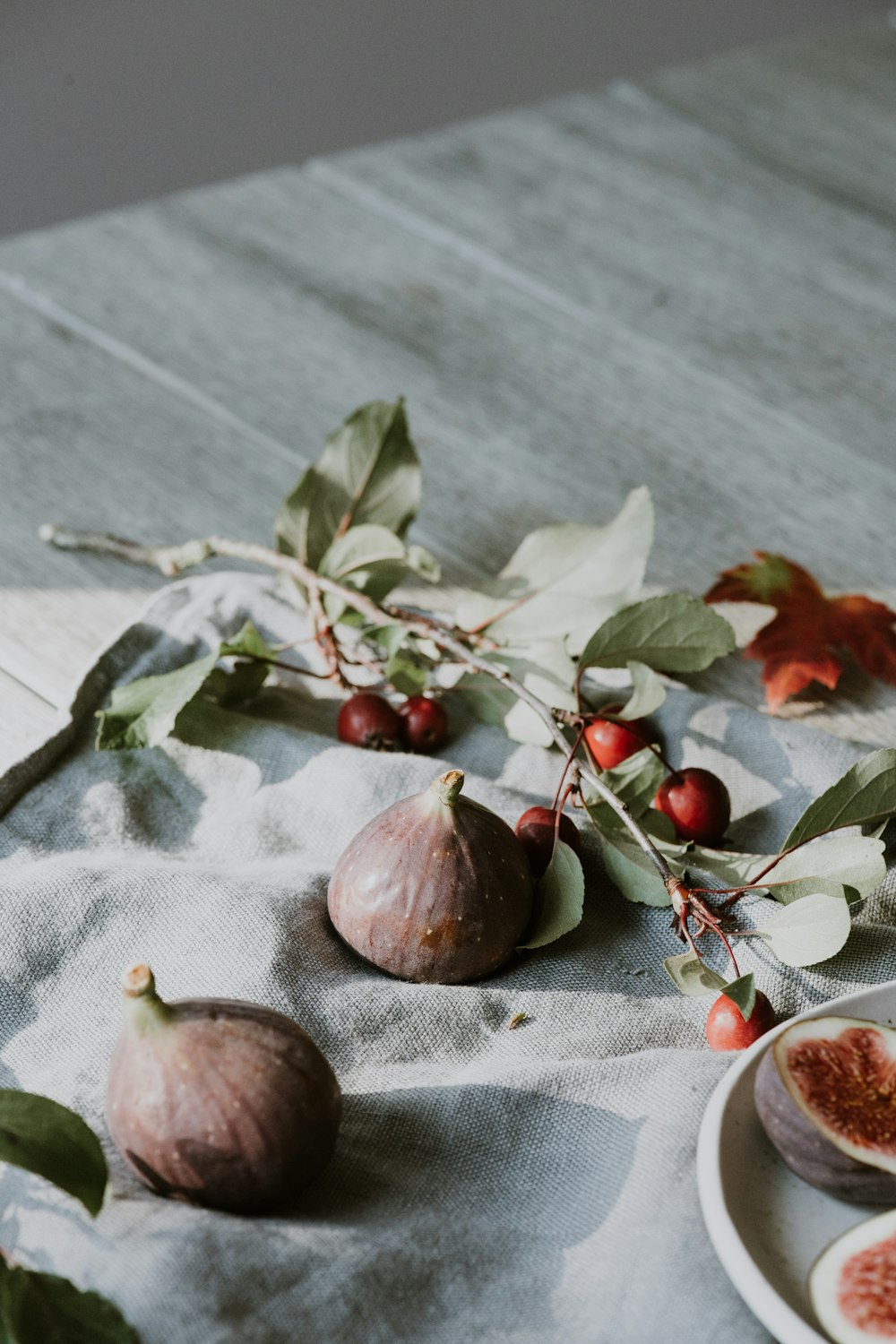 a plate of figs on a table with leaves