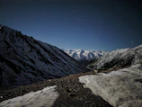 A peaceful mountain valley under a clear, sparkling night sky dotted with constellations.