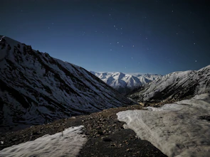 A peaceful mountain valley under a clear, sparkling night sky dotted with constellations.
