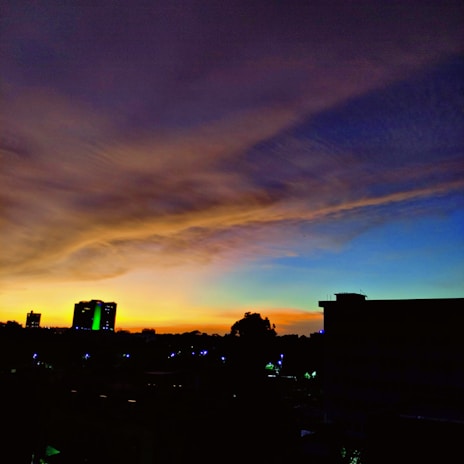 A vibrant city skyline at sunset with silhouetted buildings.