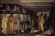 A group of people dressed in ancient attire stands on a wooden platform inside a large, ornately decorated building. The individuals engage in conversation and observation beneath a richly detailed frieze depicting figures in motion. The structure's architecture features intricate patterns along the cornice, and the dim lighting casts soft shadows around the scene.
