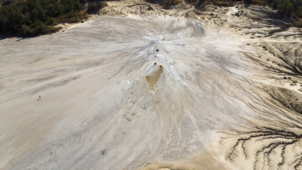 an aerial view of a sandy area with trees in the background