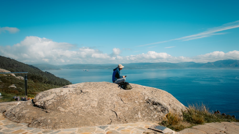 a person sitting on top of a large rock