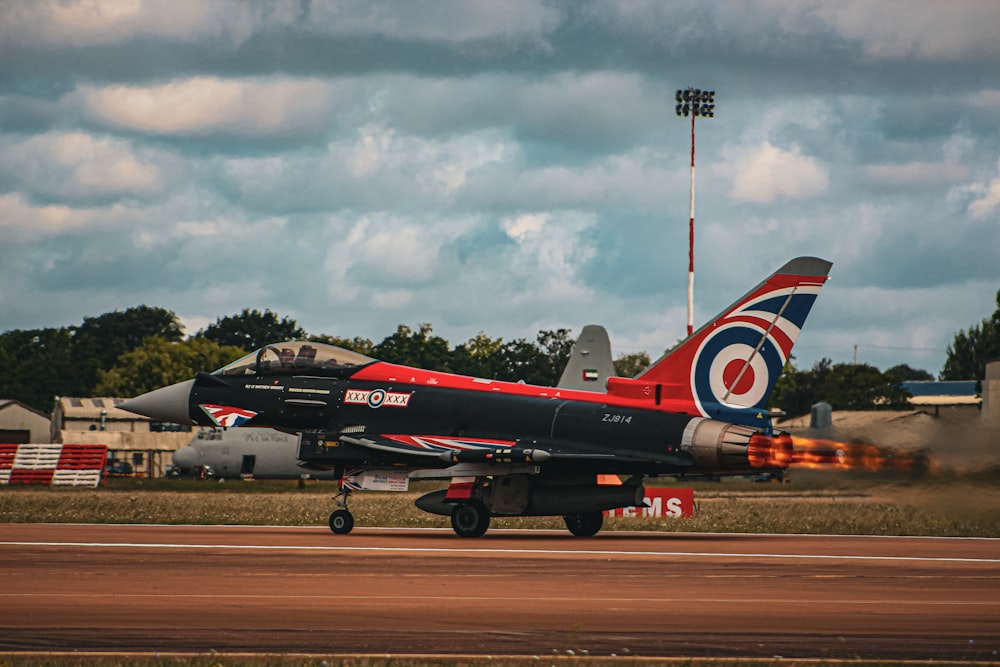 Um jato vermelho e preto está em uma pista