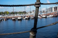 Close-up of hands tying nautical knots on thick ropes aboard a ship.