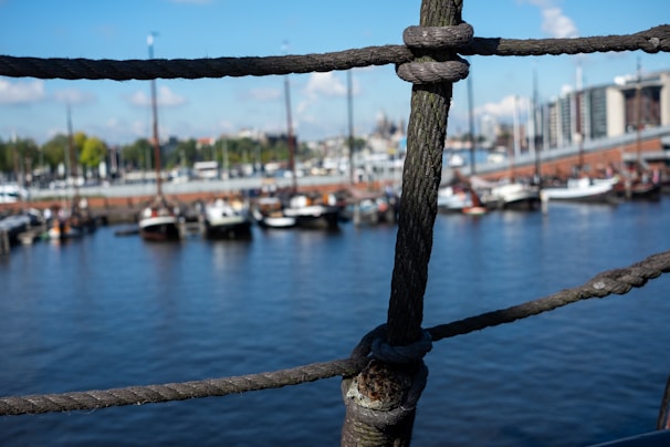 Close-up of a sailor’s hands tying a knot on thick ship ropes aboard a merchant vessel.