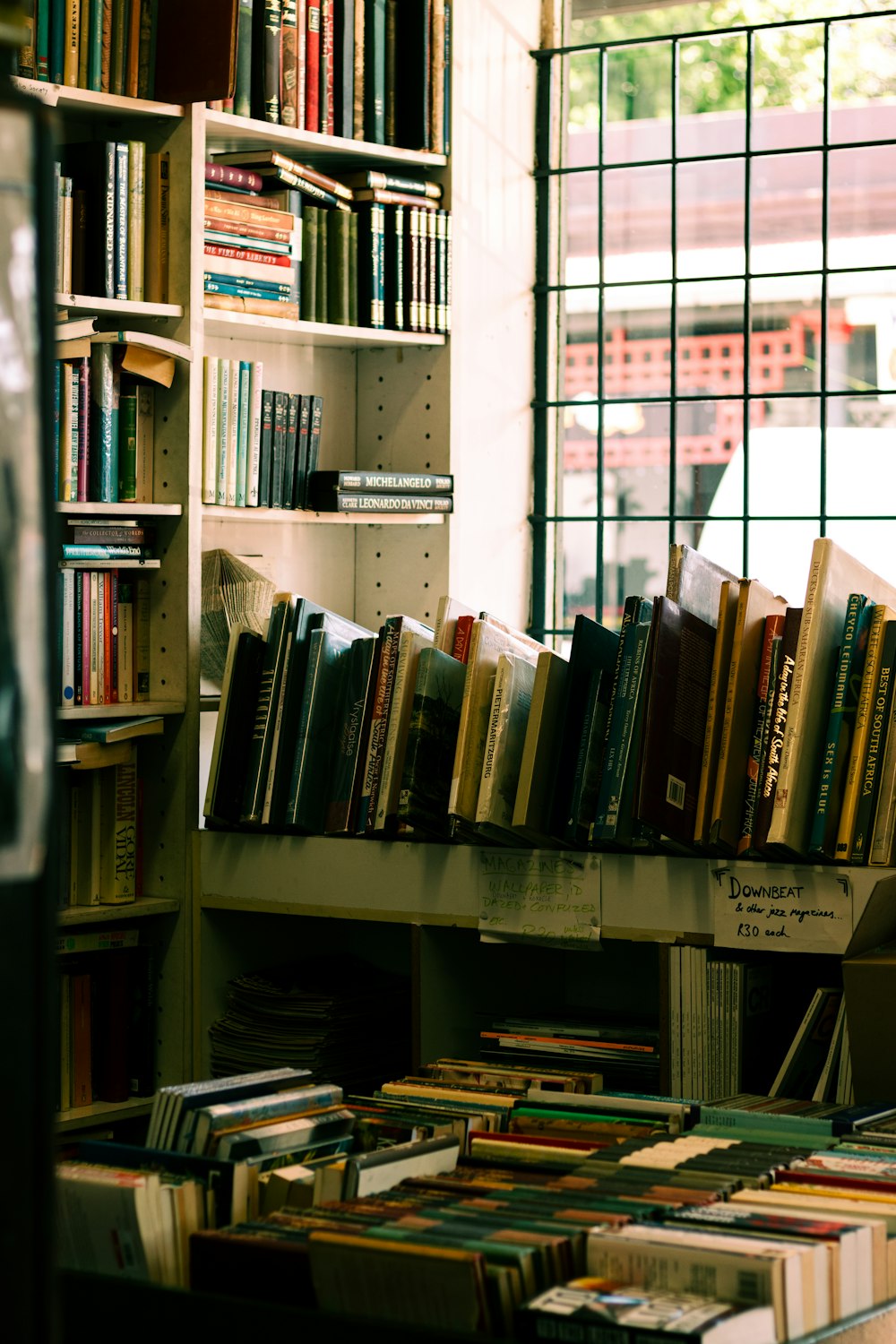 a bookshelf filled with lots of books next to a window