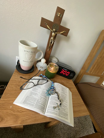 Faith-inspired corner with a small wooden cross, candles, and a journal on a rustic table.