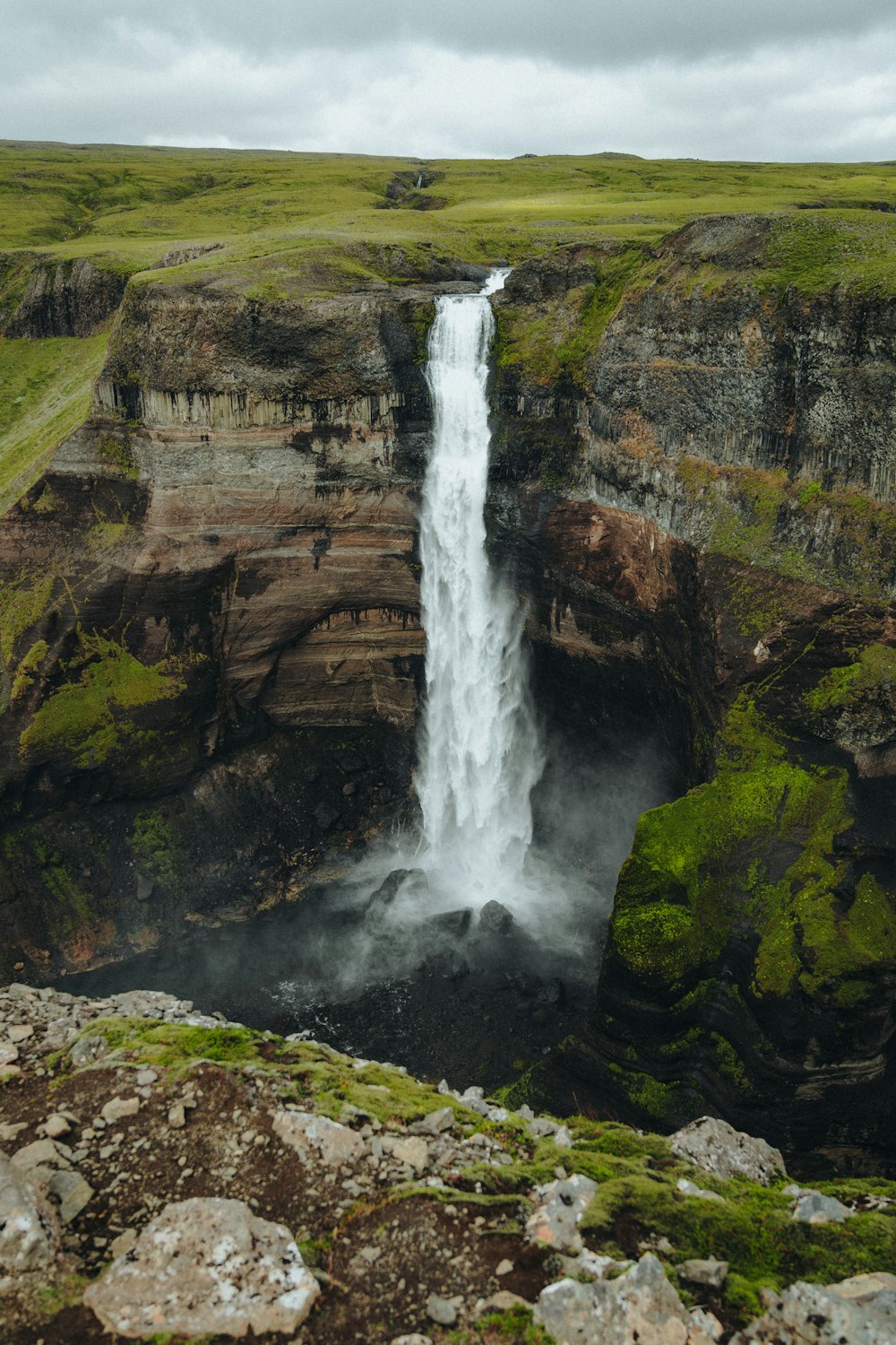 a large waterfall with green moss growing on the rocks