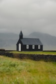 a black church with a steeple on a cloudy day