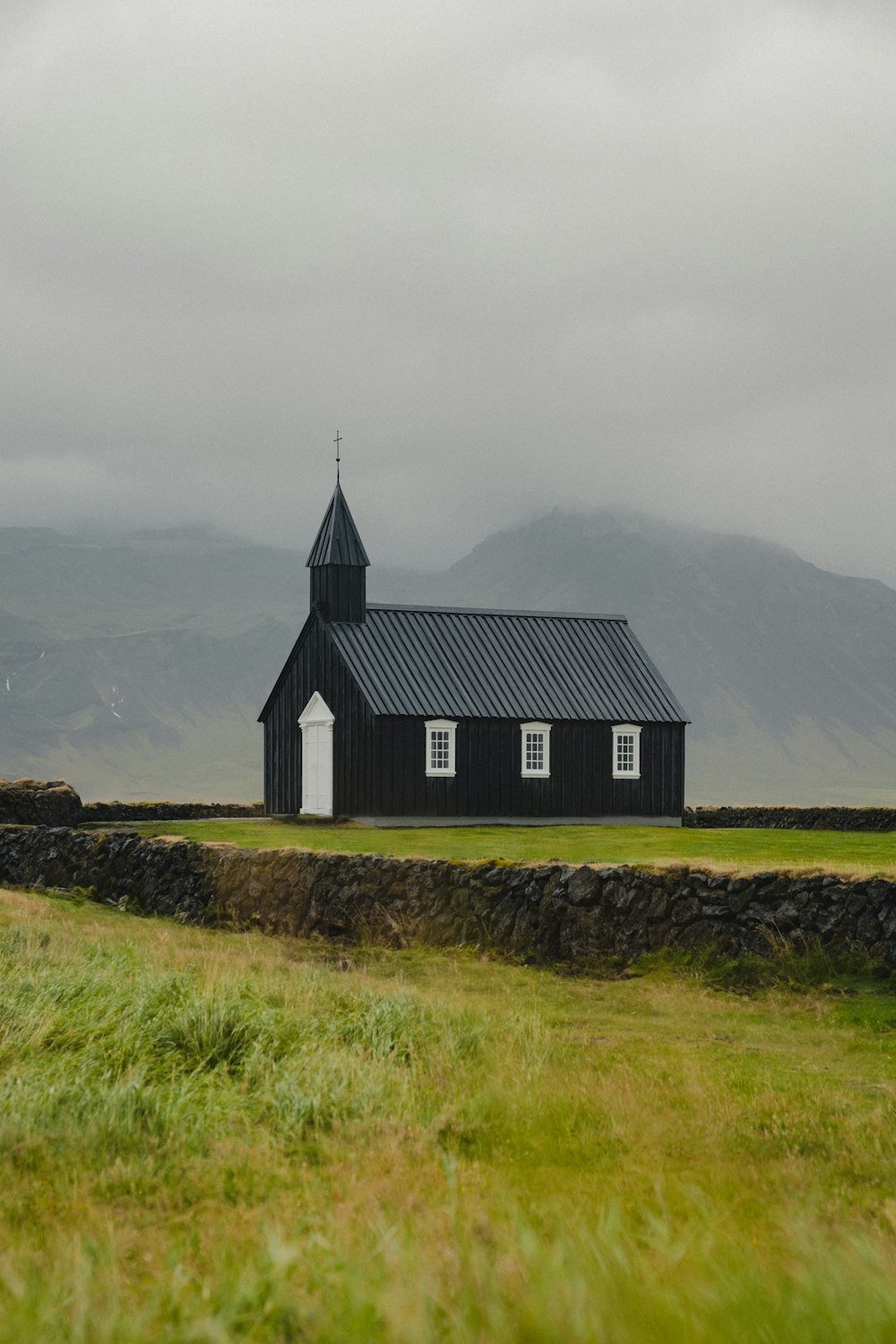Una iglesia negra con un campanario en un día nublado