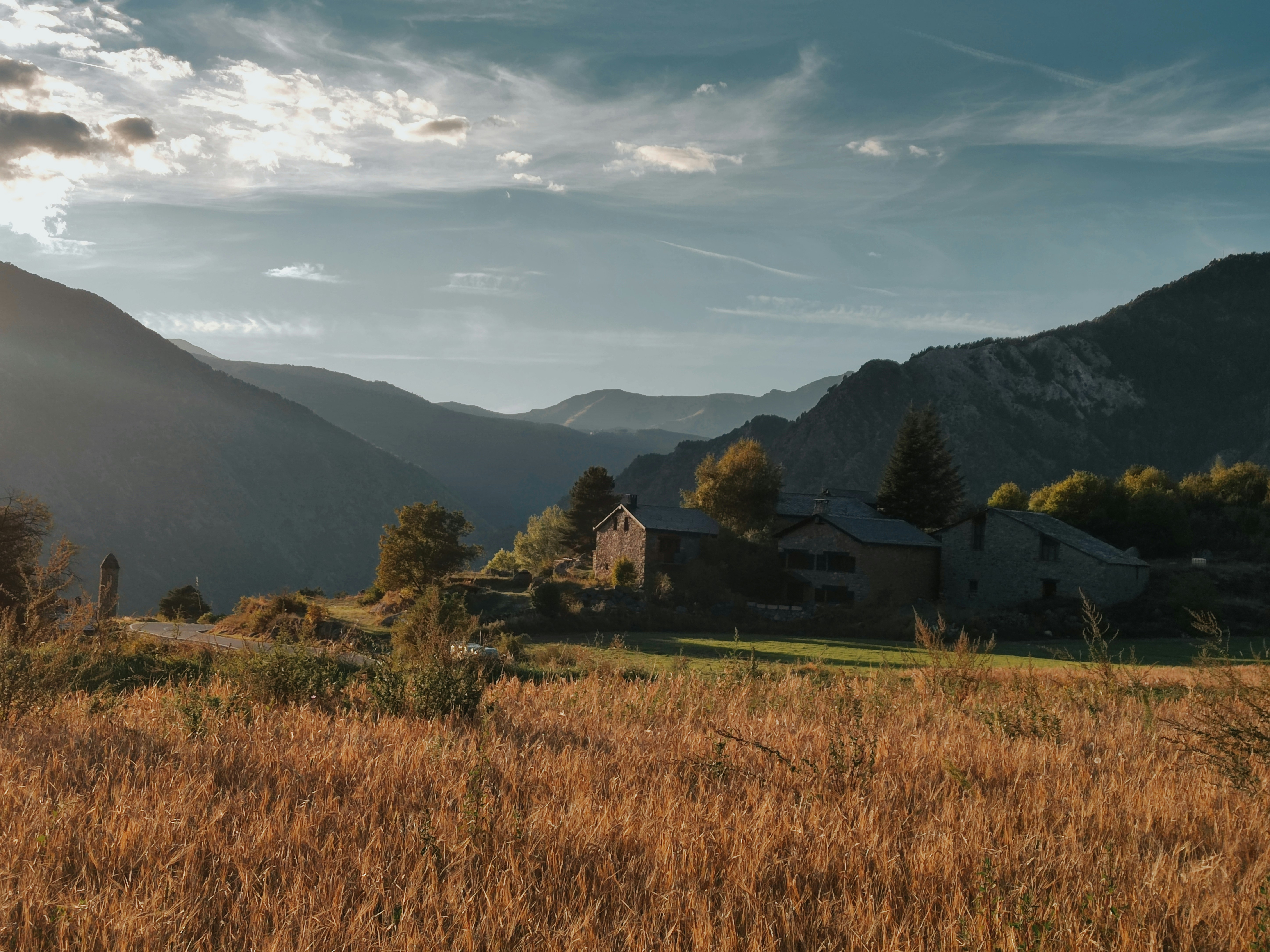 a field with a house and mountains in the background
