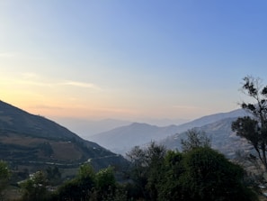 A serene landscape with rolling hills under a pastel sunset.