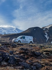 A Transporcar van with company logo parked by an industrial facility at sunrise.