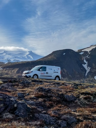 A sleek white passenger van parked in front of a scenic Minas Gerais landscape.