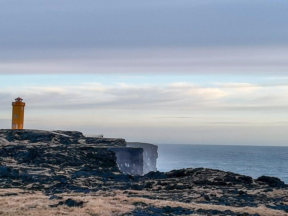 a lighthouse on top of a rocky outcropping near the ocean