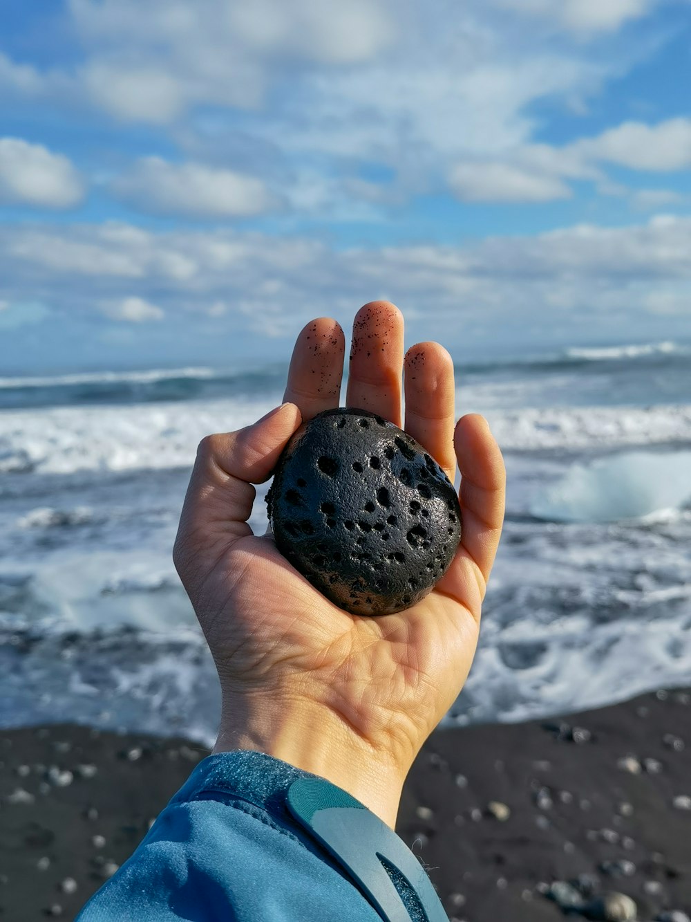 a person holding a rock in front of a body of water