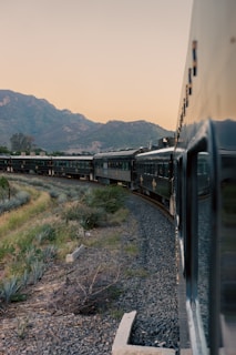 a train traveling through a rural countryside with mountains in the background