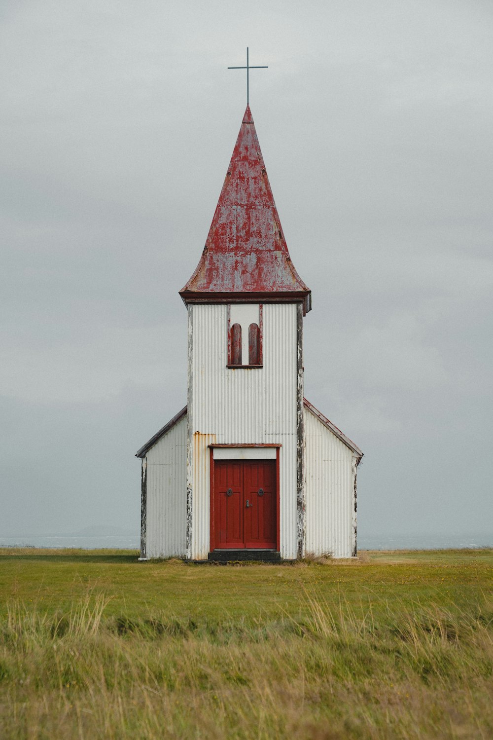 Una iglesia blanca con una puerta roja y un campanario