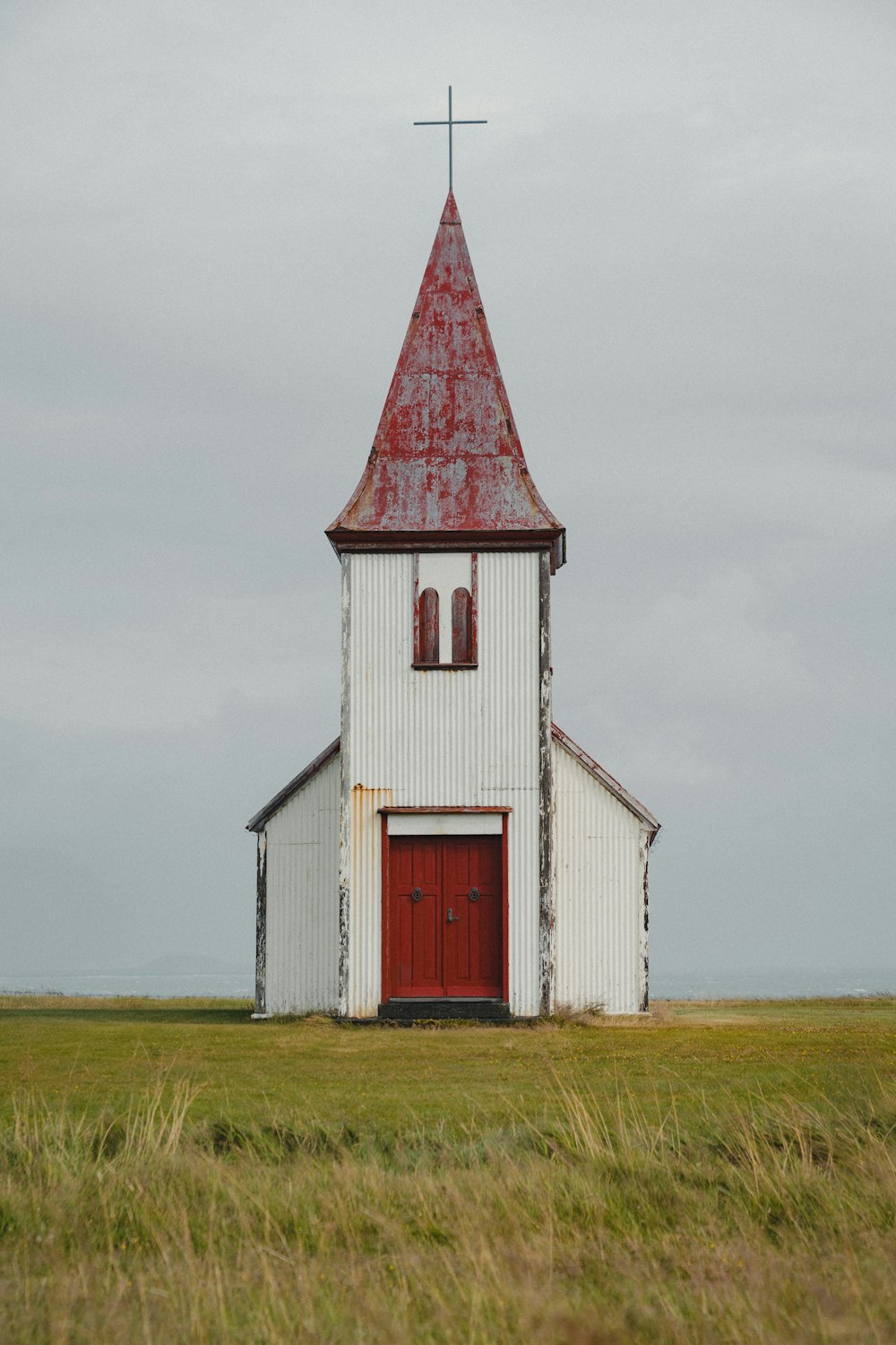 uma igreja branca com uma porta vermelha e campanário