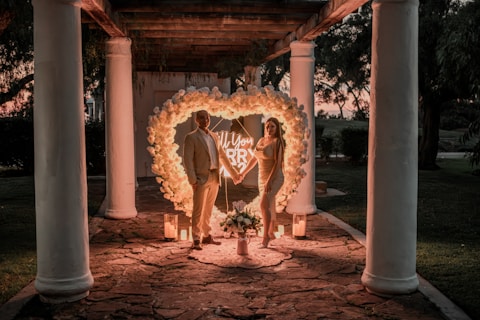 a man and a woman standing in front of a heart shaped display