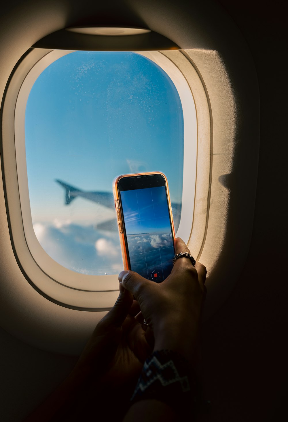 a person holding a cell phone in front of an airplane window