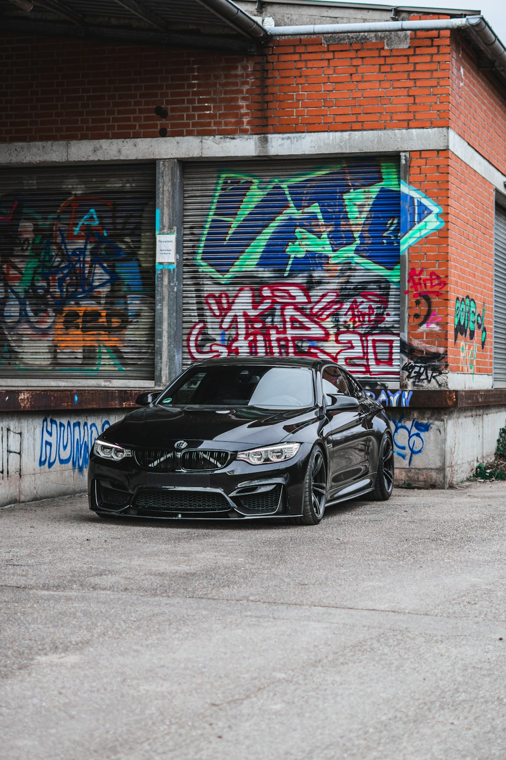 a black car parked in front of a graffiti covered building