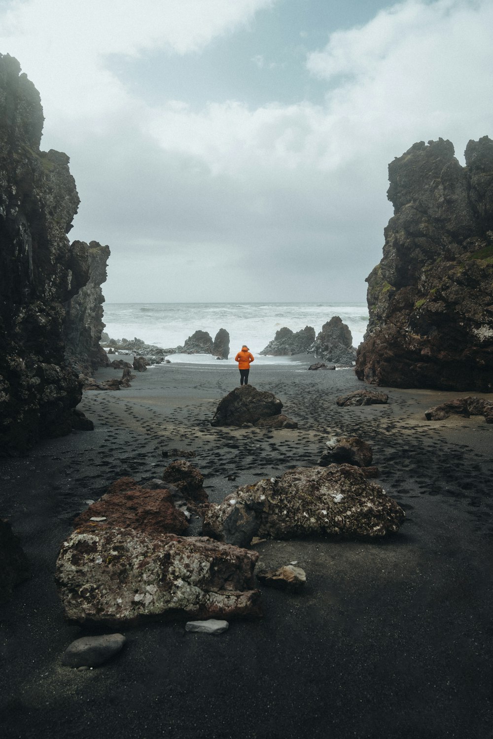 a person standing on a rocky beach next to the ocean