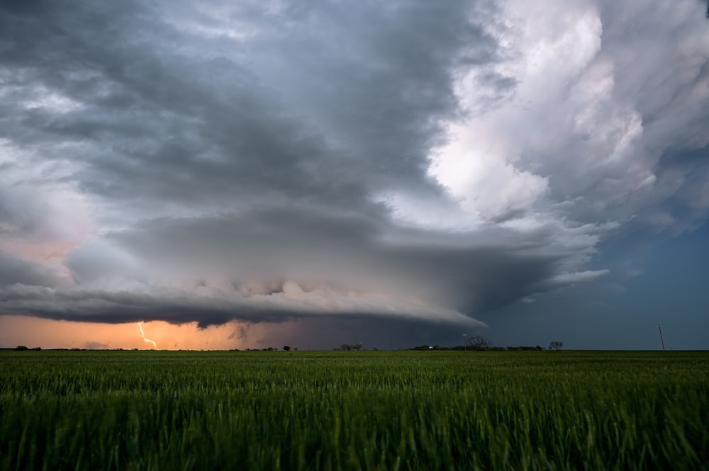 a storm is coming in over a green field