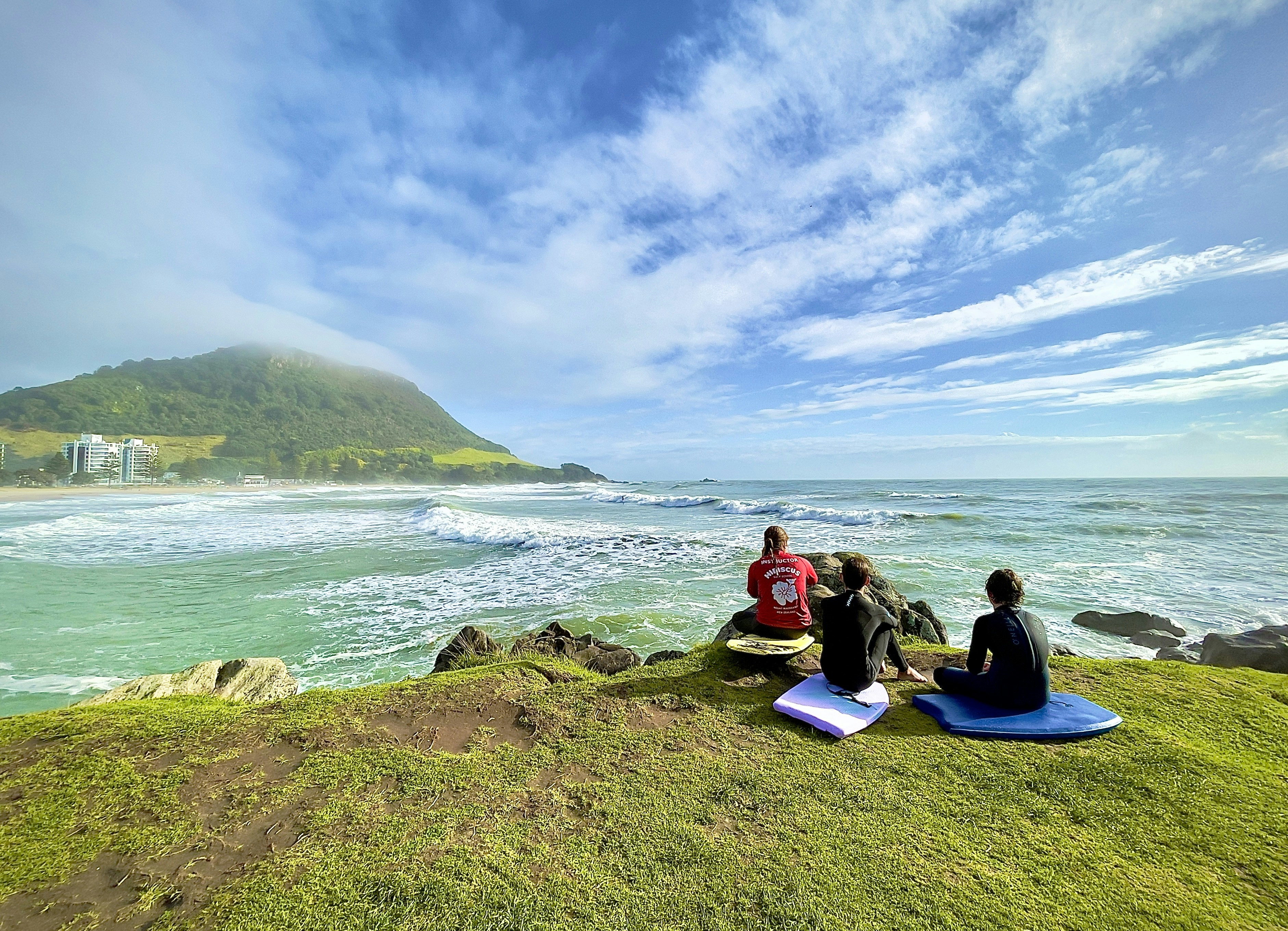A couple of people sitting on top of a lush green hillside photo – Free ...