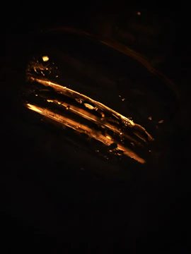 Close-up of a softly glowing abstract artwork with warm golden hues on a dark background.