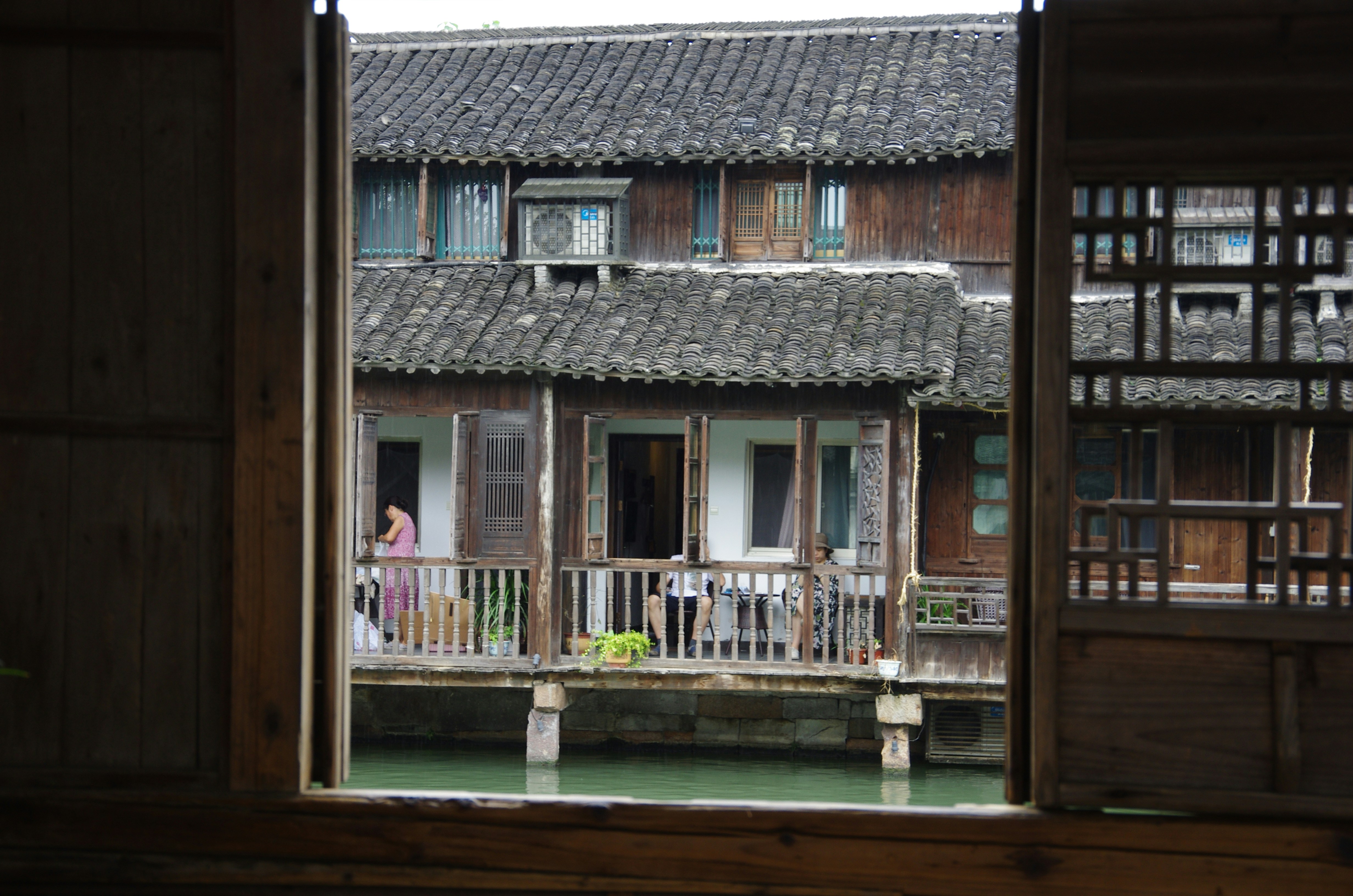 a woman standing on a balcony next to a body of water