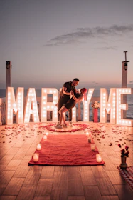 A romantic outdoor proposal setup with rose petals and soft lighting at sunset.