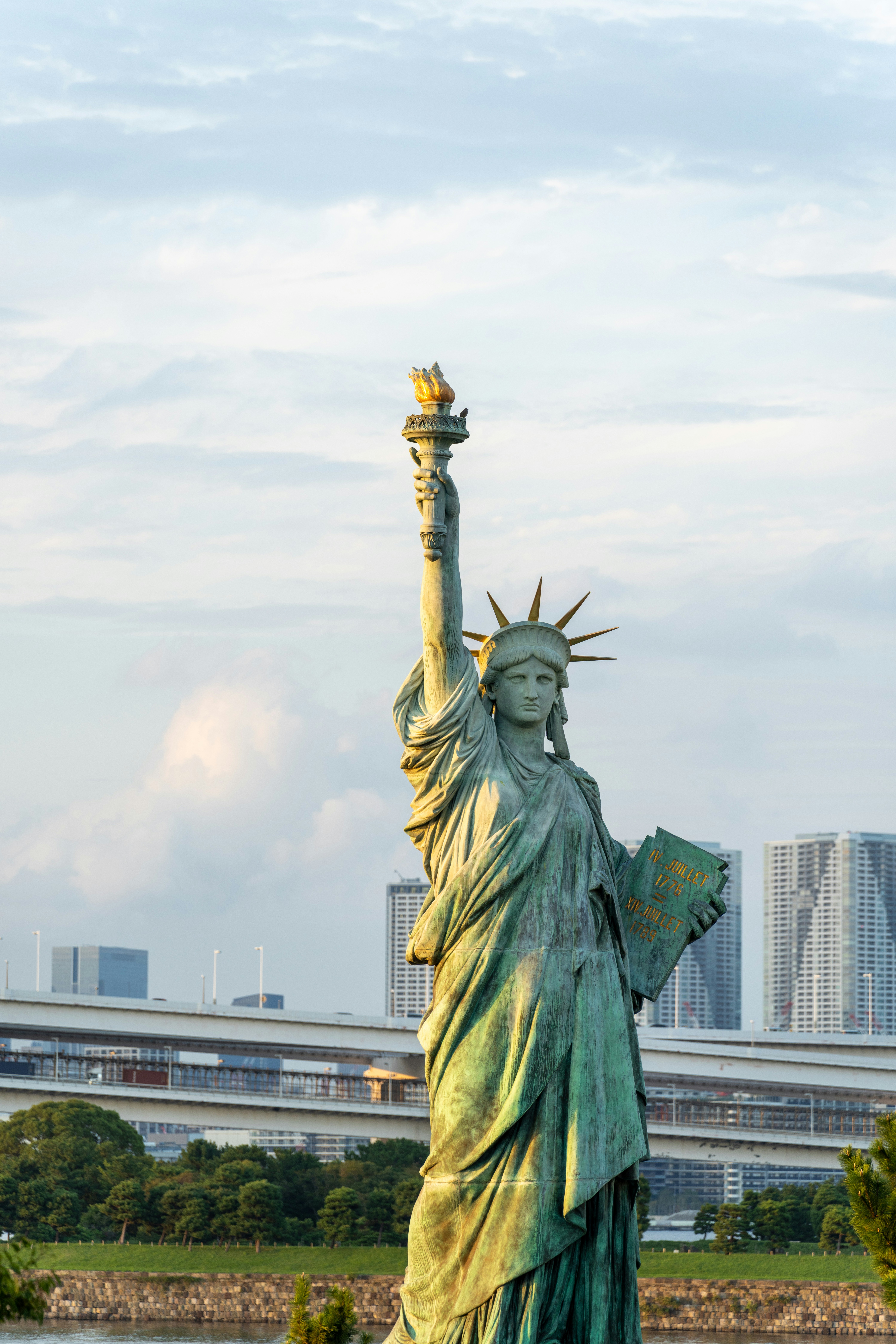 The statue of liberty stands in front of a body of water photo – Free ...