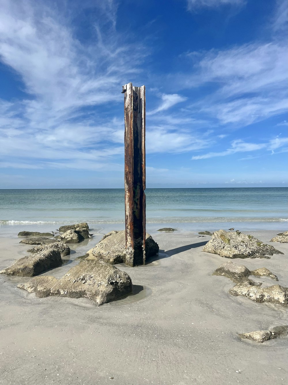 a wooden pole sticking out of the sand on a beach