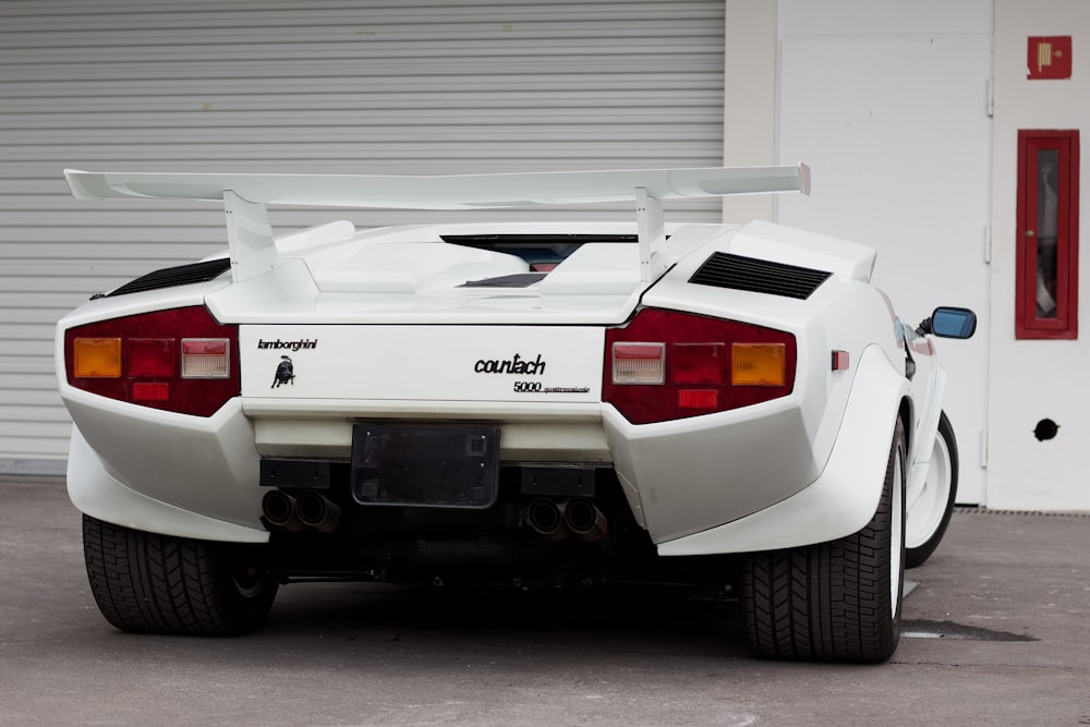 a white sports car parked in front of a garage