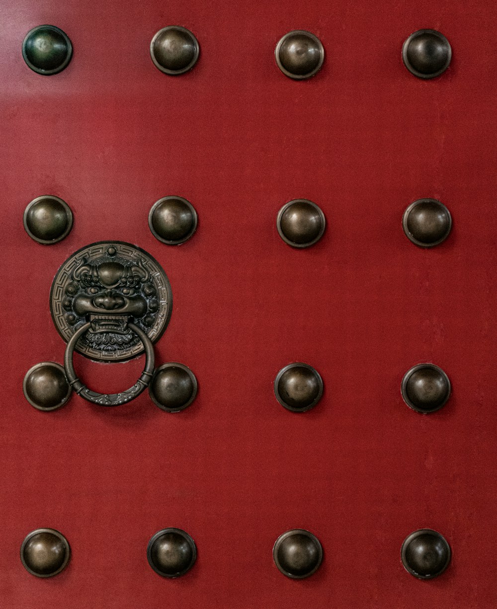 a red door with a bunch of metal knobs on it