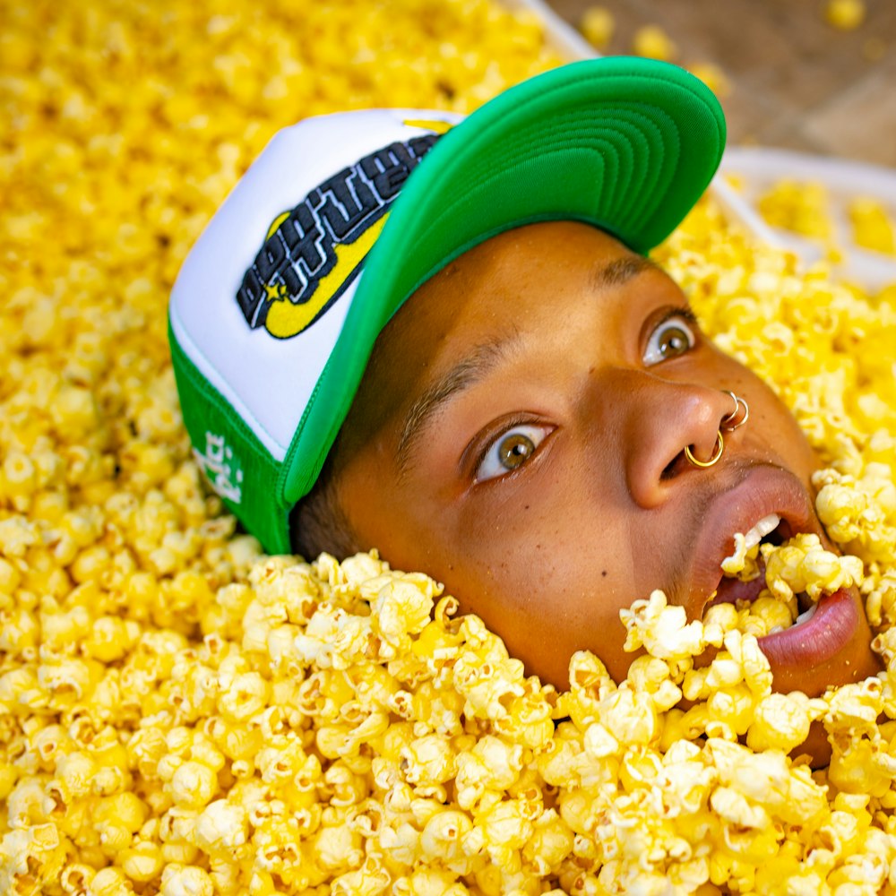 a man with a green hat is in a pile of popcorn