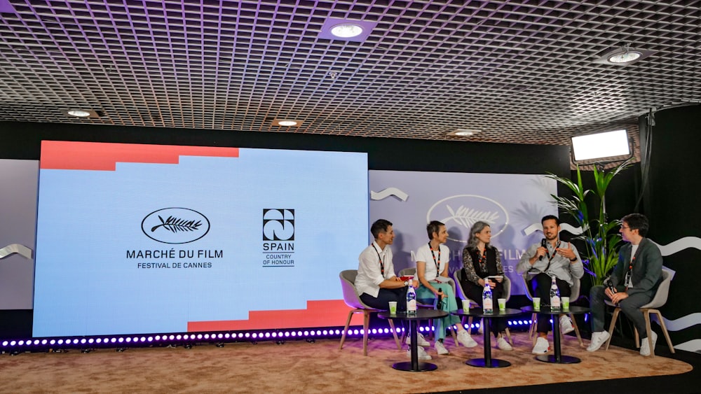 a group of people sitting on chairs in front of a screen