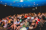 Audience applauding enthusiastically in a cozy theater setting.