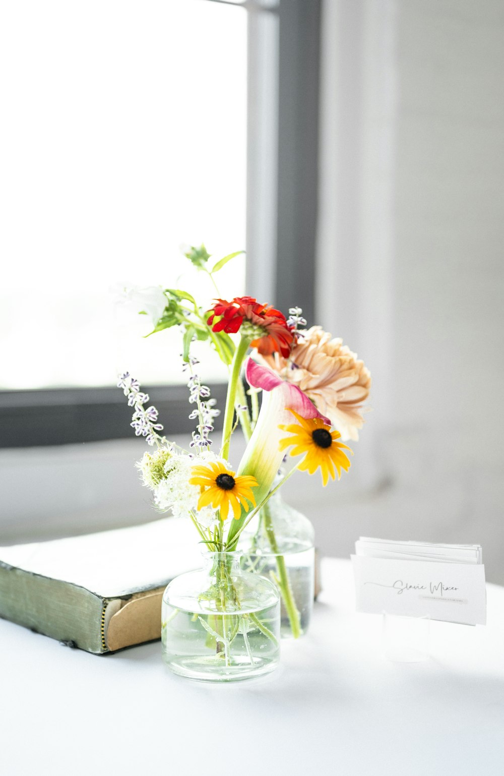 a vase of flowers sitting on a table next to a book