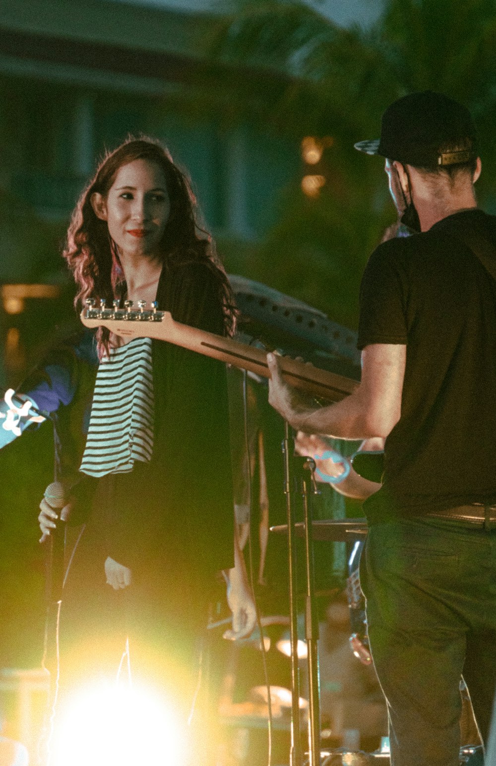 a man holding a guitar while standing next to a woman