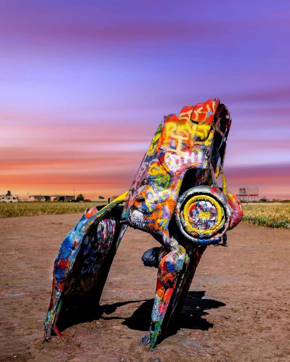 a colorful sculpture of a frog on a dirt ground