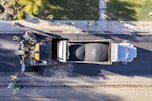 Construction workers laying asphalt on a busy road under clear sky