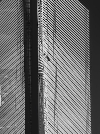 Sleek gray horizontal blinds partially open, casting gentle shadows on a minimalist white wall.