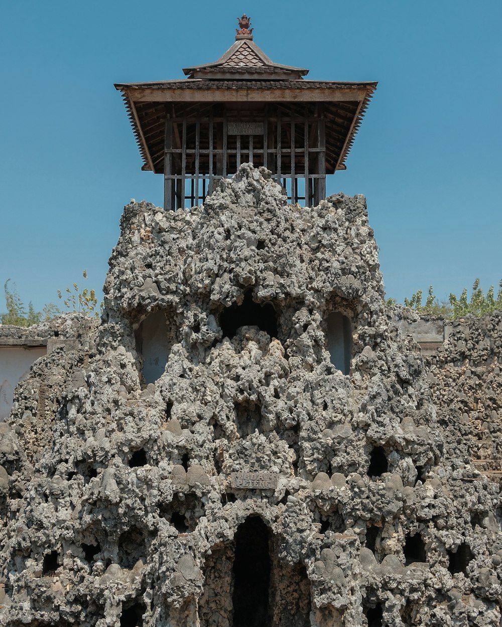 a building made of rocks with a tower in the background