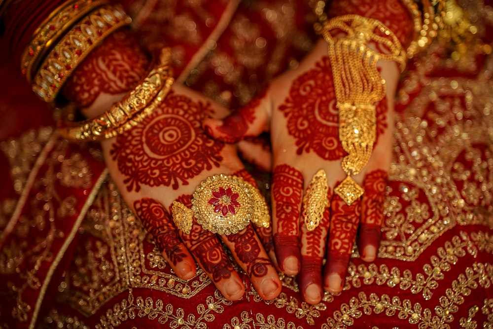 a close up of a person's hands and hands with gold jewelry on them