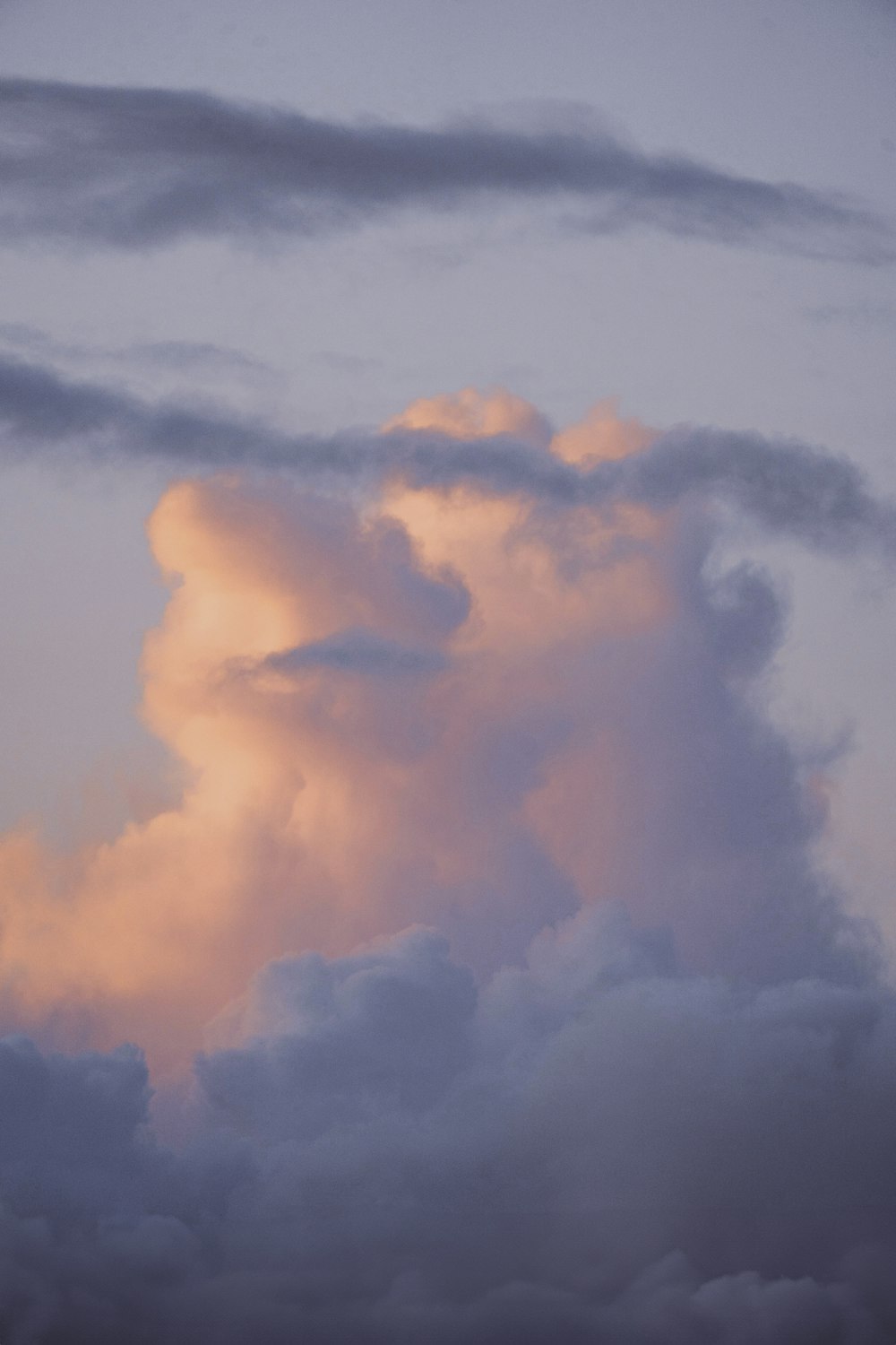 a plane flying through a cloudy sky at sunset