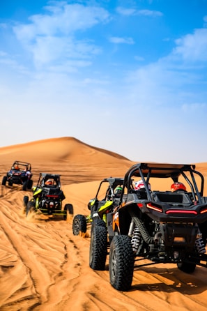 a group of four buggies driving through the desert